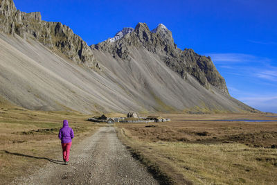 Woman walking towards viking village in stokksnes under vestrahorn mountain