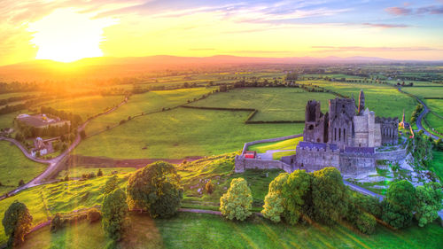 Scenic view of green landscape against sky during sunset