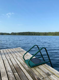 Pier on lake against clear blue sky