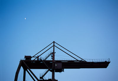 Low angle view of crane against clear blue sky