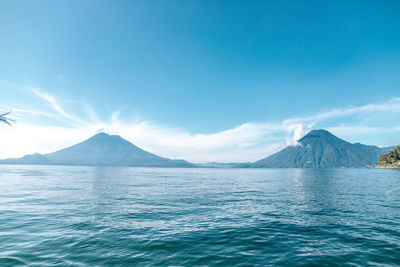 Scenic view of sea and mountains against blue sky