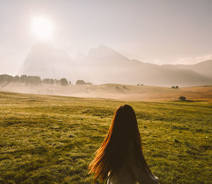 Rear view of woman standing on land during sunrise
