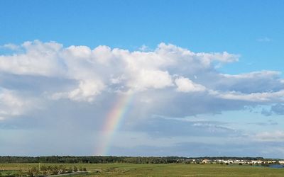 Scenic view of rainbow over field against sky