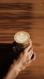 Cropped hand of man holding coffee on table