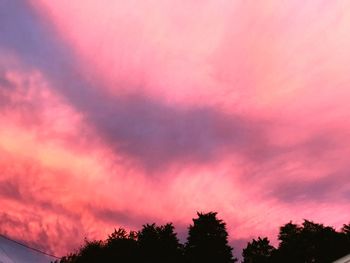 Low angle view of silhouette trees against dramatic sky