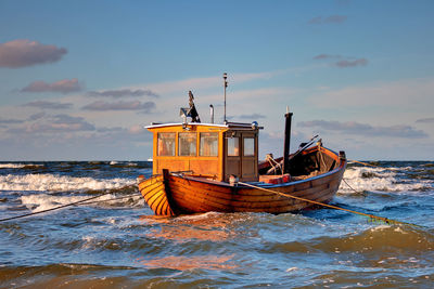 Ship moored on beach against sky during sunset