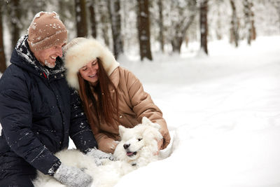 Portrait of smiling woman with dog on snow covered field
