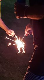 Midsection of woman with firework display at night