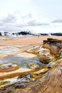 Scenic view of geyser basin against cloudy sky