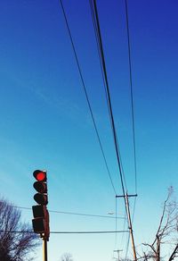 Low angle view of power lines against clear blue sky