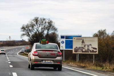 Cars on road against sky in city