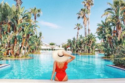 Palm trees by swimming pool against sky