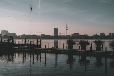 Scenic view of river by buildings against sky during sunset