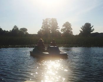 Rear view of people sitting on boat in river