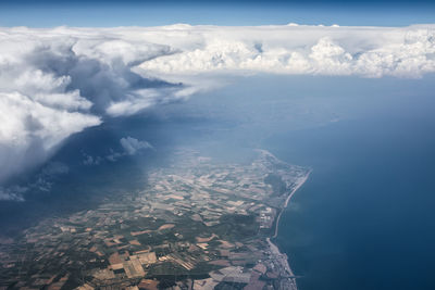 Aerial view of city by sea against sky