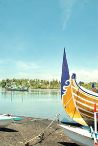 Sailboats moored on sea against sky