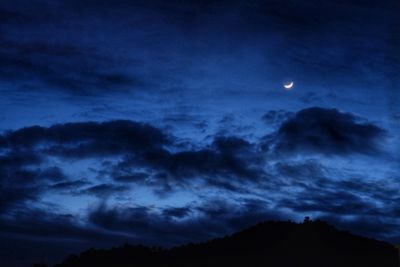 Low angle view of silhouette mountains against sky at night