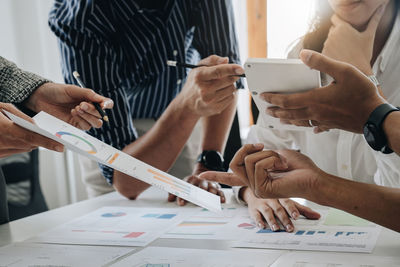 Midsection of business colleagues working on table