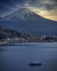 Scenic view of sea by snowcapped mountain against sky