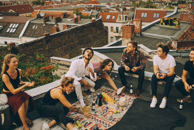 Cheerful male and female friends enjoying on terrace during rooftop party