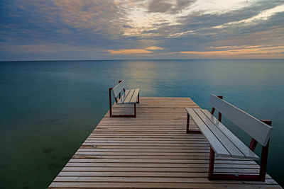 Pier over sea against sky during sunset