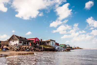 Houses by sea against sky