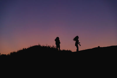 Silhouette men walking on street against sky during sunset