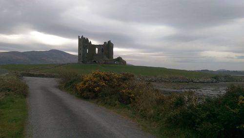 Castle on landscape against cloudy sky