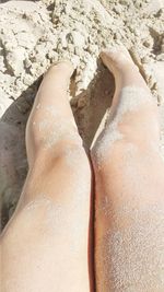 Low section of woman lying on sand at beach