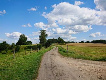 Road amidst field against sky