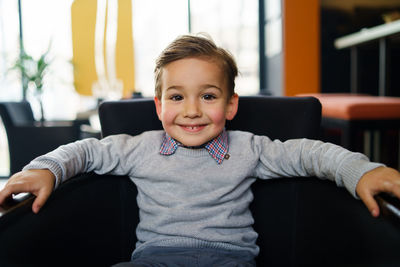 Portrait of smiling boy sitting at home