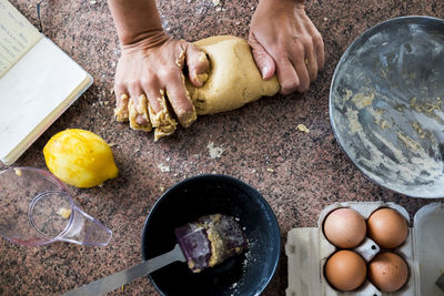 High angle view of woman kneading dough on kitchen counter