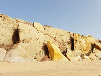 Rocks on sand against clear sky