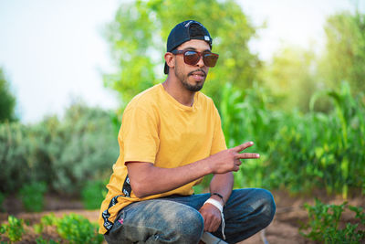 Young man wearing sunglasses sitting on plants