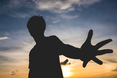 Silhouette man gesturing against sky during sunset