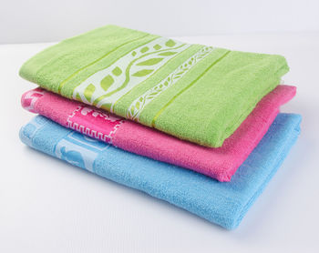 High angle view of colorful towels stacked on table against white background