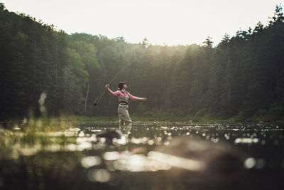 Person standing by lake against sky