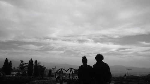 Silhouette men with people in background against sky