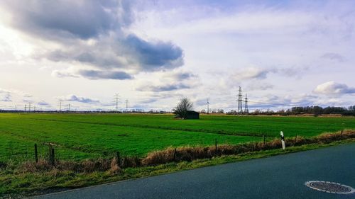 Scenic view of grassy field against cloudy sky