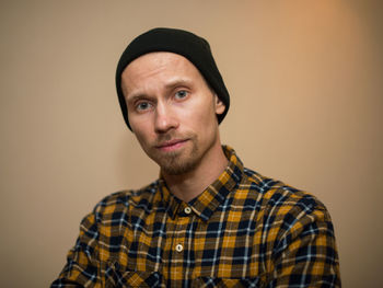 Portrait of young man wearing hat against gray background