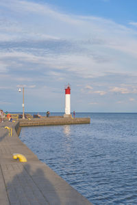 Lighthouse on pier over sea against sky