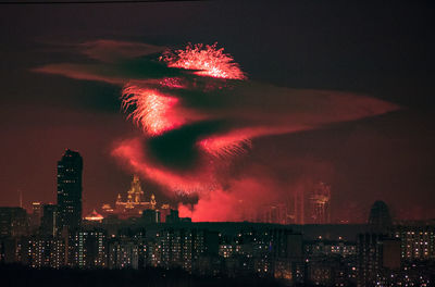 Firework display in city against sky at night