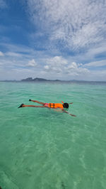 Man swimming in sea against sky