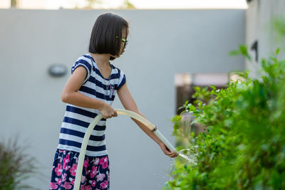 Side view of girl standing against plants