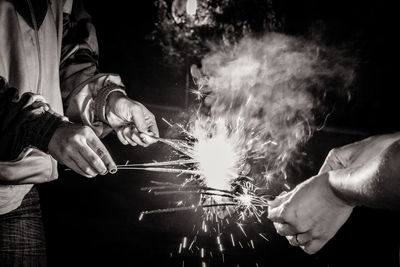 Midsection of friends holding sparklers 