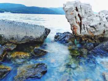 Scenic view of rocks in sea against sky