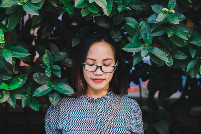 Portrait of a beautiful young woman standing against plants