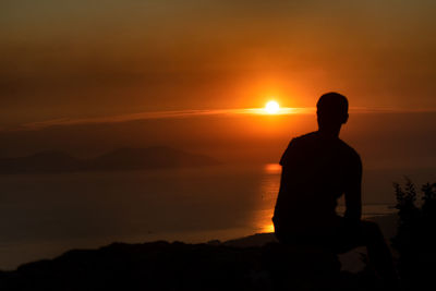 Silhouette man looking at sunset
