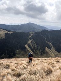 Rear view of man standing on mountain against sky