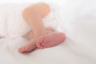 Low section of baby lying on bed